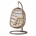 Sedia sospesa in rattan con cuscino beige e struttura in acciaio