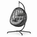 Poltrona sospesa in rattan sintetico con struttura in metallo e cuscino grigio